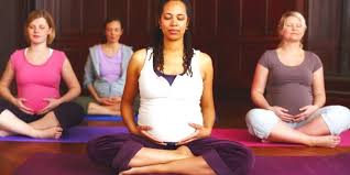 pregnant woman sitting meditating holding her bump