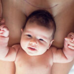 Baby lying on mums legs with a caesarean scar showing