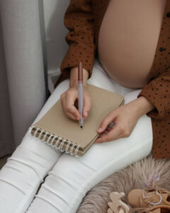 A pregnant woman sits and writes a birth plan